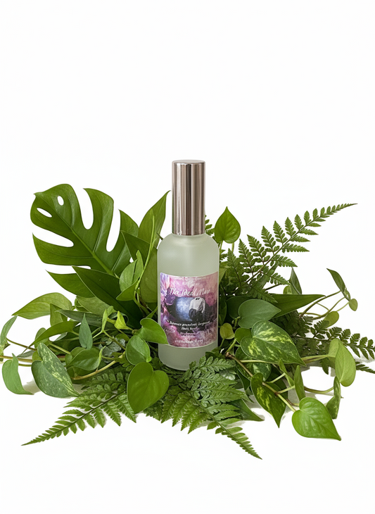 Frosted bottle with a purple label on a wooden surface with green leaves in the background